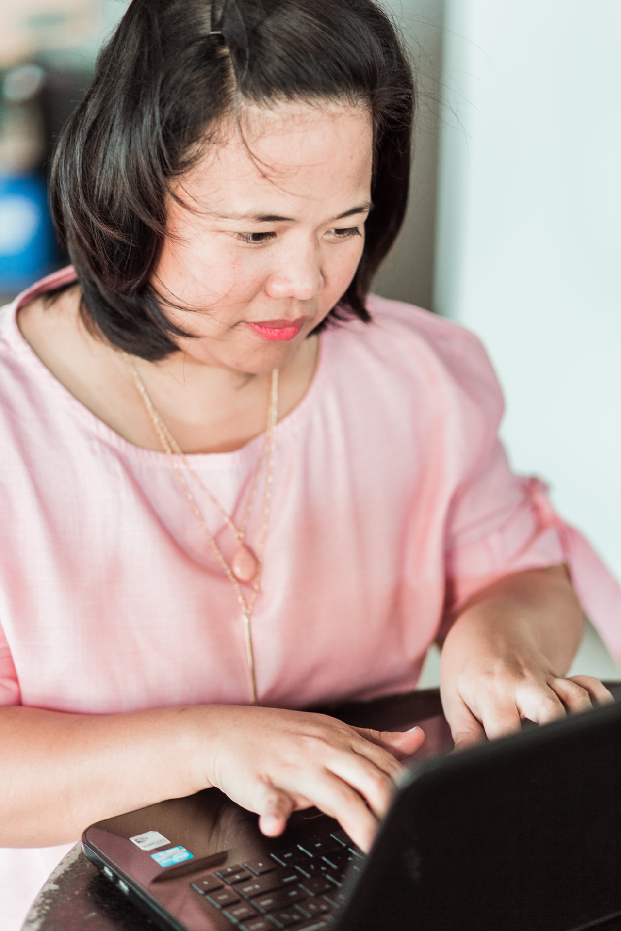 Eden Bregala in a pink blouse working on a laptop